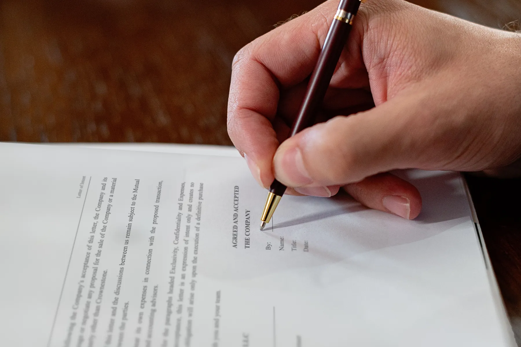 An owner's hand with a pen at the acceptance line of a letter of intent from Crownestone Capital